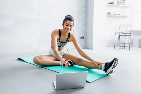 Sonriente Mujer Afroamericana Ropa Deportiva Sentado Alfombra Fitness Cerca Computadora — Foto de Stock