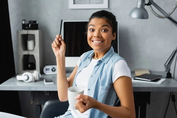 Emocionado Afroamericano Freelancer Mirando Cámara Mientras Sostiene Pluma Taza Fondo — Foto de Stock