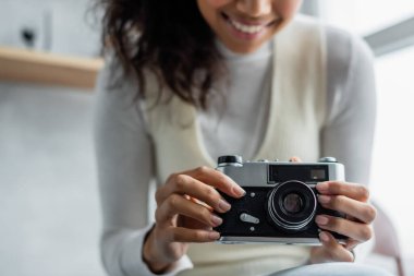 Gülümseyen Afro-Amerikan kadının eski model fotoğraf makinesiyle görüntüsü bulanık.