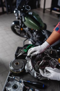 Kırpılmış arka planda parçalanmış vites kutusu ve motosiklet yakınındaki mekanik görüntüsü