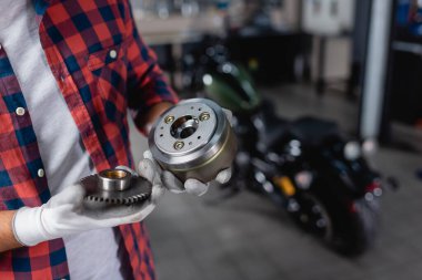 Eldivenli teknisyen motosiklet şanzımanının vites dişlilerini tutuyor.