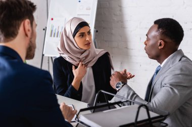 ciddi bir Arap iş kadını Afrikalı Amerikalı iş ortağıyla görüşmesinde, çevirmenin yakınında, bulanık bir ön plan