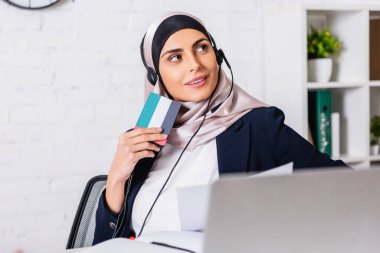 Uae bayrağı sembollü dijital tercüman elinde kulaklıkla gülümseyen Arap tercüman, bulanık önplan
