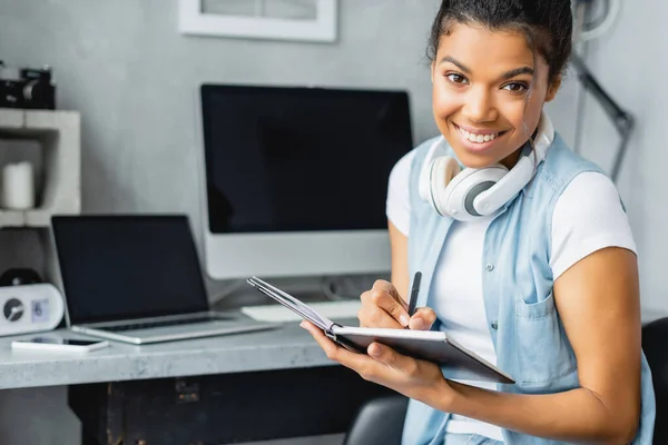 Cheerful African American Freelancer Looking Camera Writing Notebook Laptop Computer — Stock Photo, Image