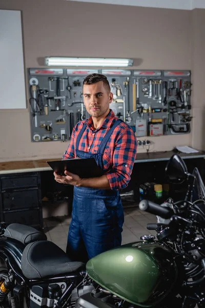 Young Technician Overalls Looking Camera While Standing Clipboard Motorcycle — Stock Photo, Image