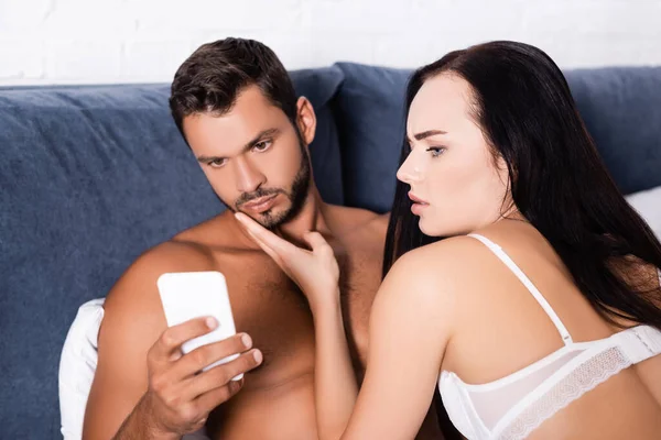 Shocked Woman Lingerie Looking Smartphone Hand Displeased Shirtless Man Bed — Stock Photo, Image