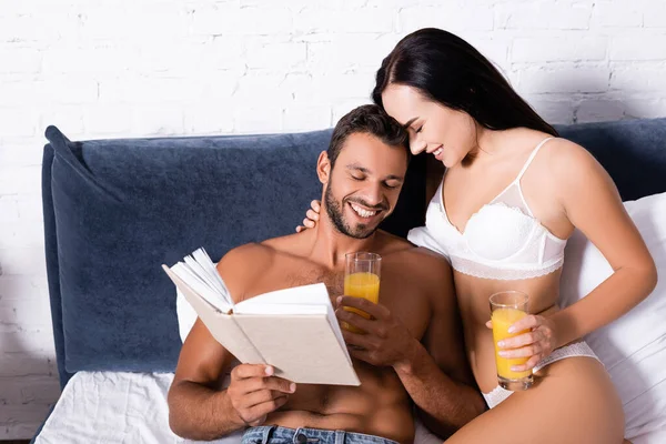 Ευτυχισμένο Σέξι Ζευγάρι Ποτήρια Χυμό Και Βιβλίο Γελώντας Στο Κρεβάτι — Φωτογραφία Αρχείου