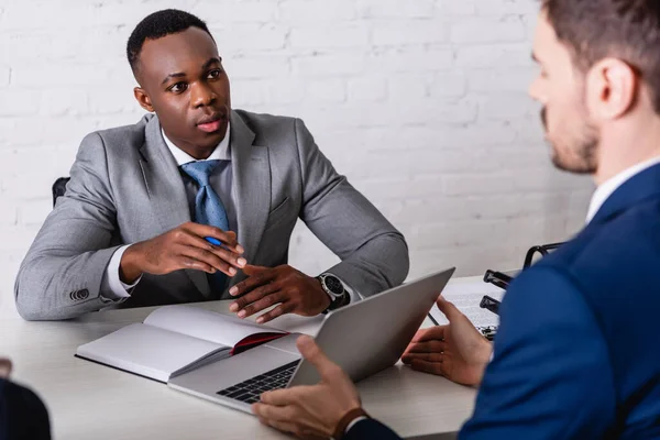 Afrikansk Amerikansk Affärsman Tittar Affärspartner Visar Laptop Suddig Förgrund — Stockfoto