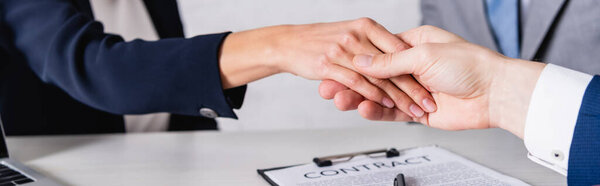 partial view of business partners shaking hands near contract, banner
