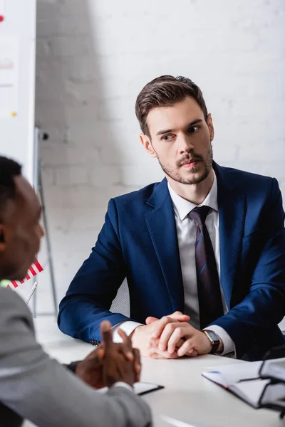 Serieuze Europese Zakenman Zoek Naar Afrikaanse Amerikaanse Zakenpartner Wazig Voorgrond — Stockfoto