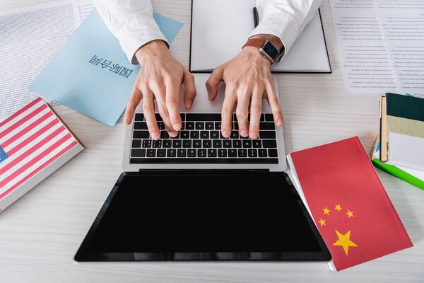 partial view of translator typing on laptop near paper with chinese hieroglyphs. Translation: "international contract"