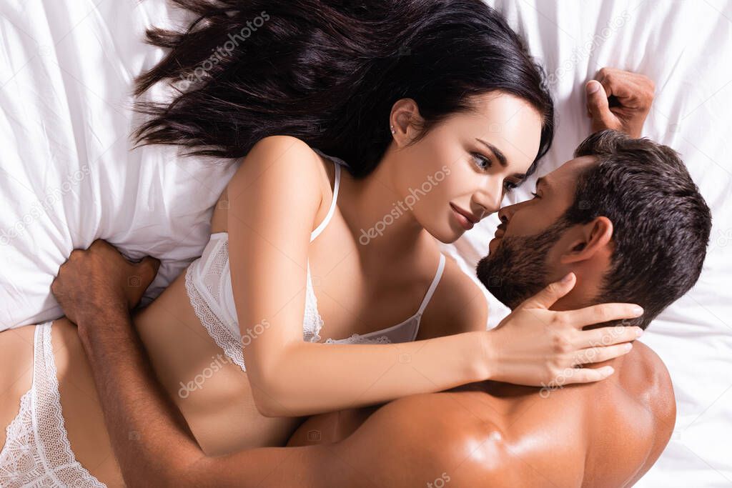 high angle view of sexy man looking at brunette woman in underwear lying on bed