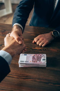 Avro banknotlarının yanında el sıkışan işadamları görüşü