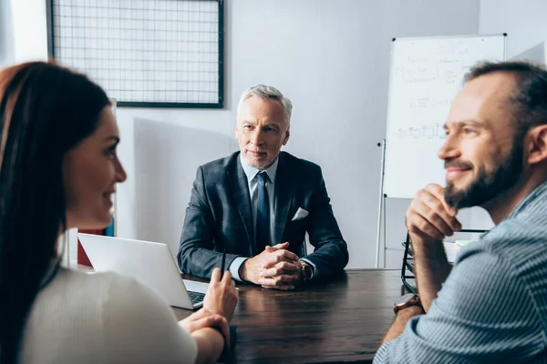 Mature Investor Looking Smiling Businesspeople Talking Blurred Foreground Office — Stock Photo, Image