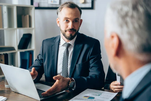 Zakenman Wijst Naar Laptop Buurt Van Kranten Investeerder Wazig Foreground — Stockfoto