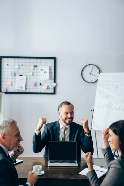 Smiling Businessman Showing Yeah Gesture Laptop Blank Screen Colleagues Blurred — Stock Photo, Image