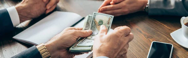 Cropped View Businessman Holding Dollar Banknotes Smartphone Colleagues Blurred Background — Stock Photo, Image