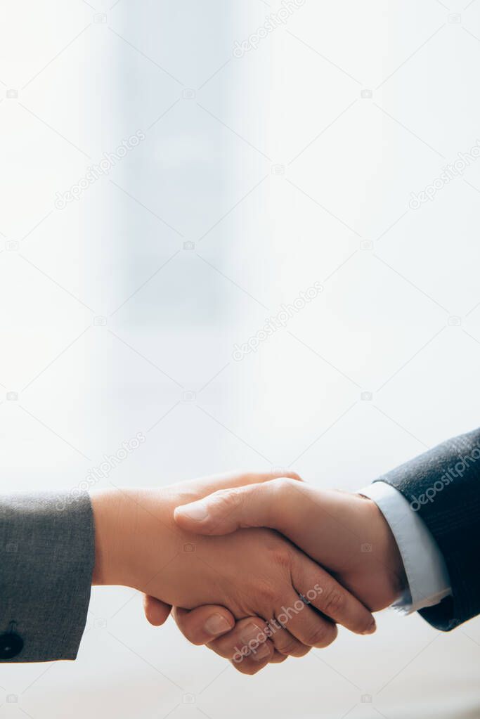 Cropped view of business partners shaking hands in office  