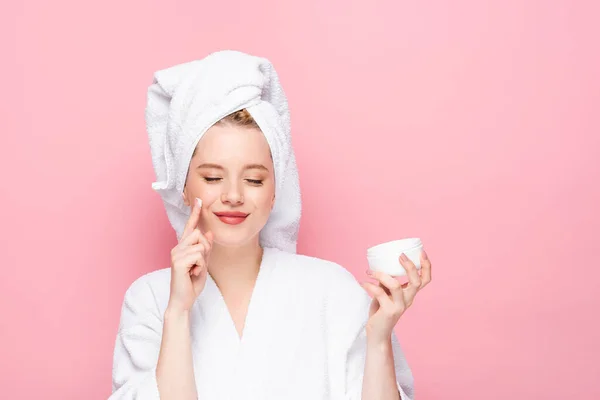 Młoda Kobieta Szlafroku Ręcznik Głowie Trzymając Krem Kosmetyczny Pokazując Palec — Zdjęcie stockowe