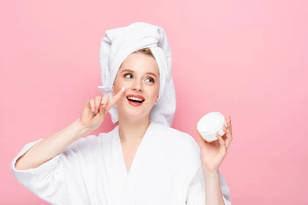 Jovem Feliz Toalha Roupão Cabeça Segurando Creme Cosmético Mostrando Dedo — Fotografia de Stock