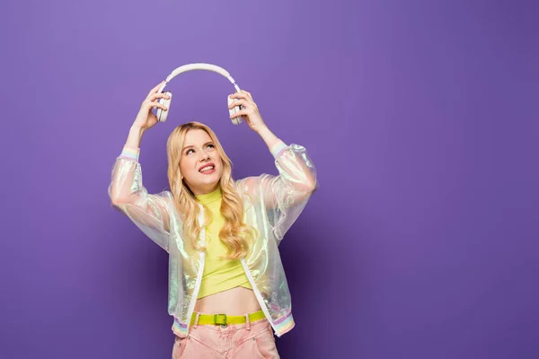 Verwarde Blonde Jonge Vrouw Kleurrijke Outfit Koptelefoon Paarse Achtergrond — Stockfoto