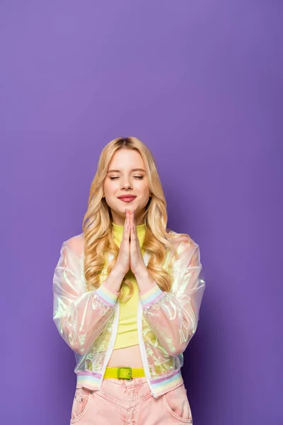 Blonde Young Woman Colorful Outfit Praying Hands Purple Background — Stock Photo, Image