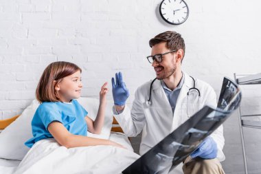 Mutlu kız ve doktor hastanede röntgen çektiriyorlar.