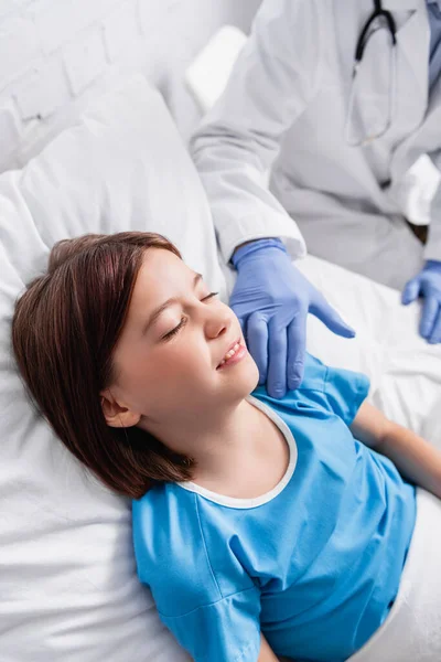 Doctor Touching Child Lying Hospital Bed Closed Eyes Blurred Background — Zdjęcie stockowe