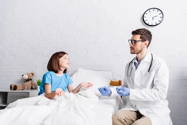 Pediatrician Eyeglasses Girl Bed Gesturing While Talking Hospital — Stock Photo, Image