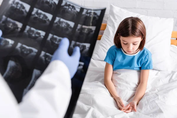 Doctor Apuntando Rayos Cerca Chica Molesta Sentada Cama Hospital — Foto de Stock