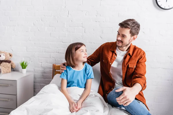 Sorridente Homem Abraçando Feliz Filha Sentado Cama Hospital — Fotografia de Stock