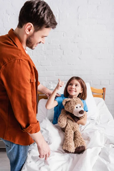Mutlu Kız Oyuncak Ayıyı Tutuyor Hastanede Babasına Baş Parmağını Gösteriyor — Stok fotoğraf