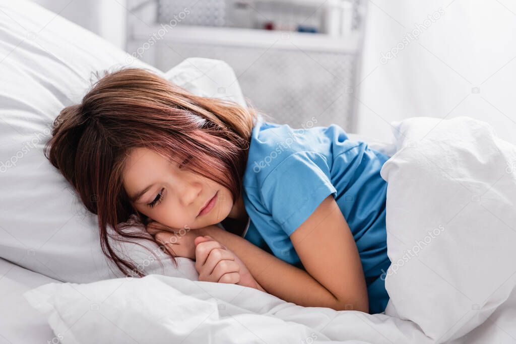 diseased, sad girl lying on bed in hospital