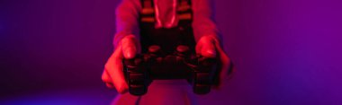 KYIV, UKRAINE - 27 Kasım 2020: Mor arka planda elinde joystick tutan kadının kısmi görüntüsü, afiş