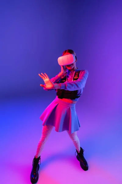 Повна Довжина Молодої Жінки Гарнітурі Віртуальної Реальності Жестикулює Фіолетовому Фоні — стокове фото