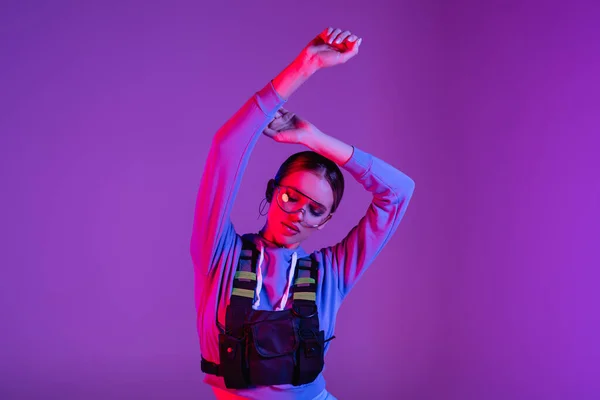 Стильная Женщина Солнечных Очках Руками Над Головой Позирующими Фиолетовом — стоковое фото