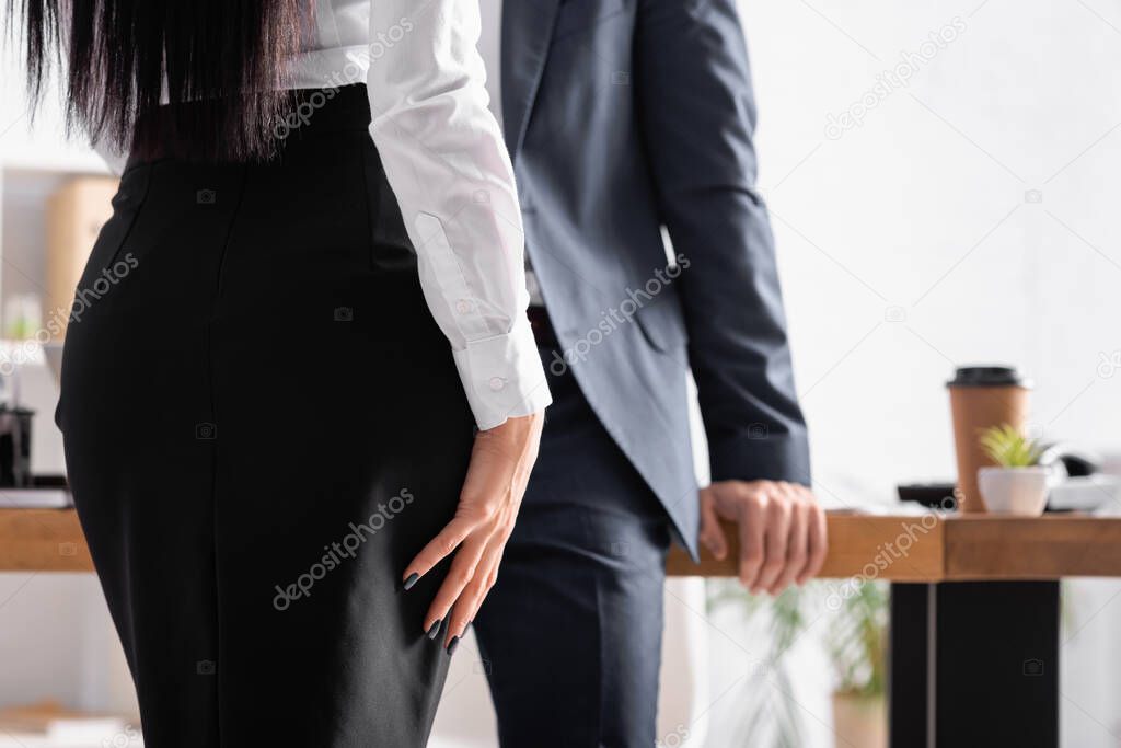 partial view of secretary near businessman on blurred background
