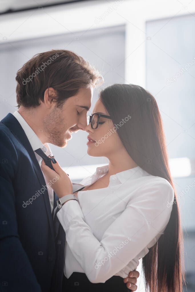 smiling businessman hugging secretary touching his tie in office