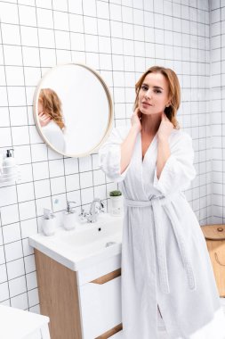 woman in bathrobe looking at camera in bathroom clipart