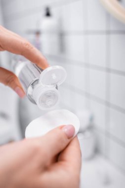 Banyoda elinde toner ve pamuklu ped olan bir kadın. 