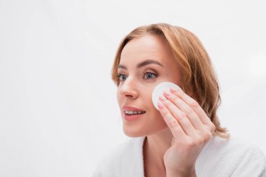 Yüzünde pamuk pedi olan toner kullanan pozitif bir kadın. 