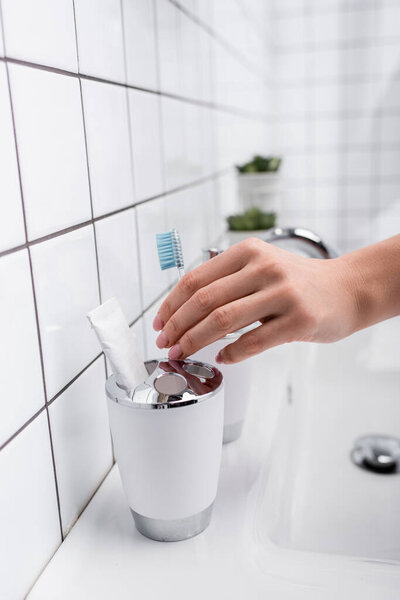 cropped view of woman taking toothbrush in bathroom 