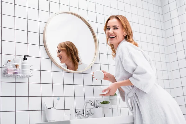 Cheerful Woman Holding Jar Face Cream Looking Camera Bathroom — Stock Photo, Image