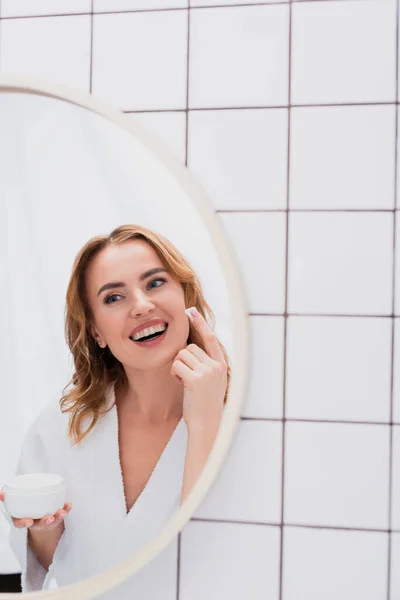 Glad Kvinna Tillämpa Ansiktskräm Medan Tittar Spegeln — Stockfoto