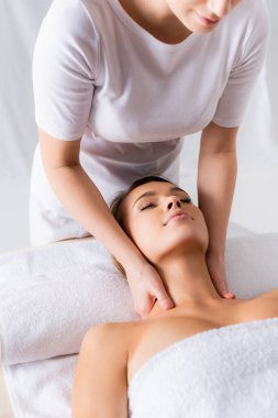 Bayan masör, spa salonundaki memnun müşteriye boyun masajı yapıyor. 