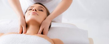 Masör, spa salonunda gözleri kapalı müşteriye boyun masajı yapıyor.