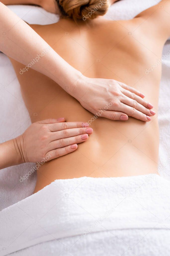 partial view of masseur massaging client on massage table 