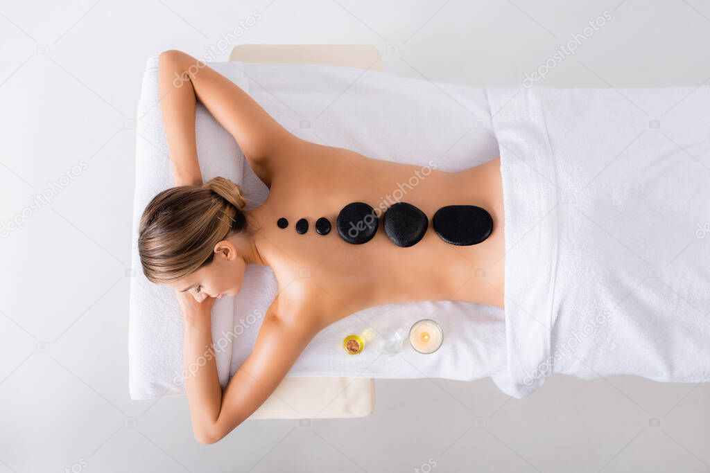 top view of young woman getting hot stone massage in spa salon