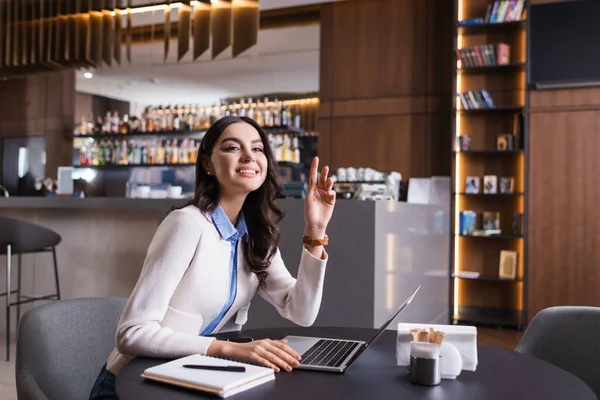 Smiling Freelancer Raising Hand Looking Away While Sitting Laptop Restaurant — Stock Photo, Image