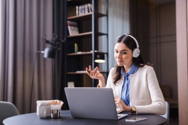 Restoranda dizüstü bilgisayarın yanında oturan kulaklıklı genç serbest çalışan.